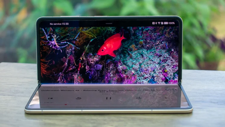 Honor Magic V5 folded on a desk, showing a video on the main display