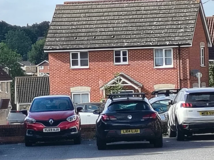 10x zoom of a red house with cars out front