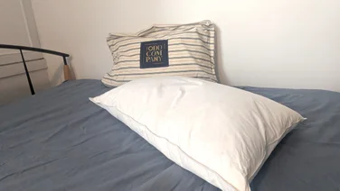 One Odd Company Luxury Pillow on a mattress with its carry bag behind it
