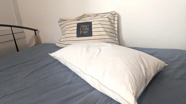 One Odd Company Luxury Pillow on a mattress with its carry bag behind it