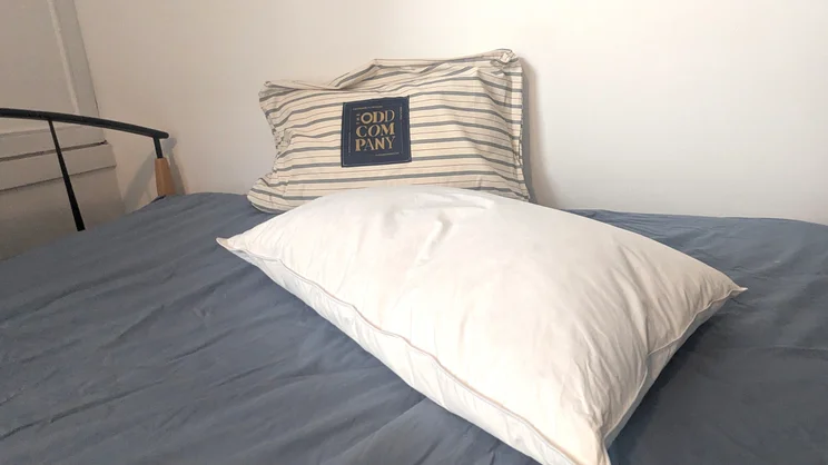One Odd Company Luxury Pillow on a mattress with its carry bag behind it