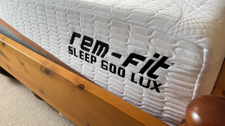 A closeup of the corner of the REM-Fit 600 Lux Elite mattress, on a wooden bed frame
