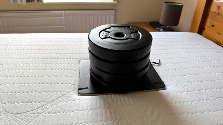 Testing sinkage of the REM-Fit 600 Lux Elite mattress using a notebook and series of 2.5kg weight plates