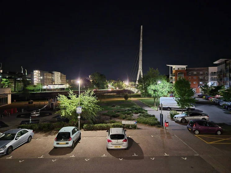A car park at night with the city skyline in the distance