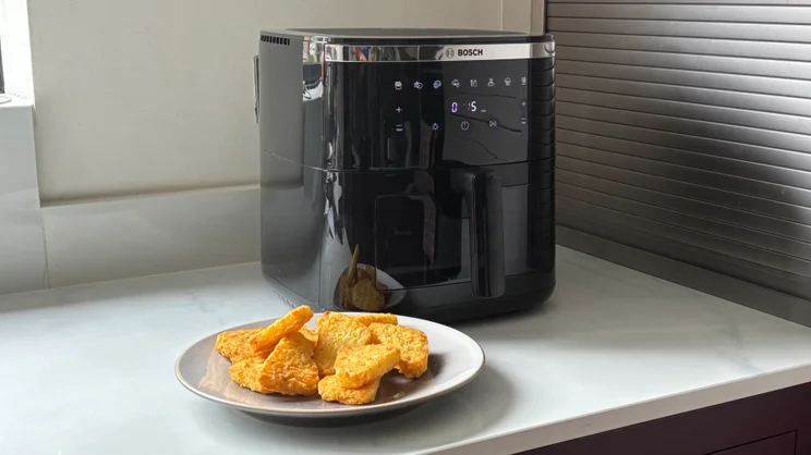 The Bosch Series 6 Air Fryer with a plate of hash browns in front of it