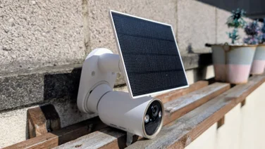 The Tapo C460 security camera pictured set on a wood shelf from the left side