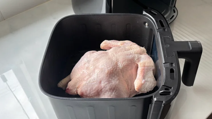 The drawer the Bosch Series 6 Air Fryer holding a raw whole chicken