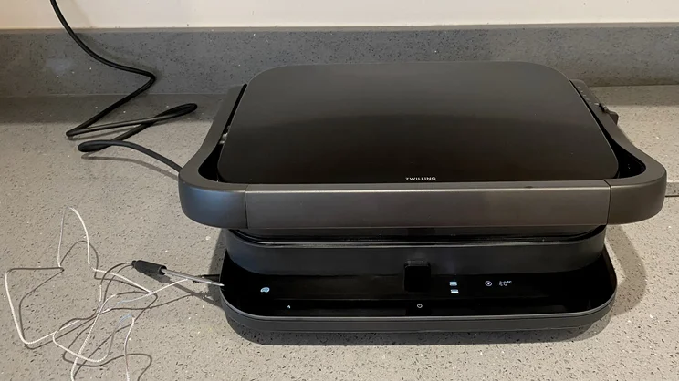 The Zwilling Enfinigy Contact Grill, closed, on a kitchen countertop. A thermometer probe is attached to the side