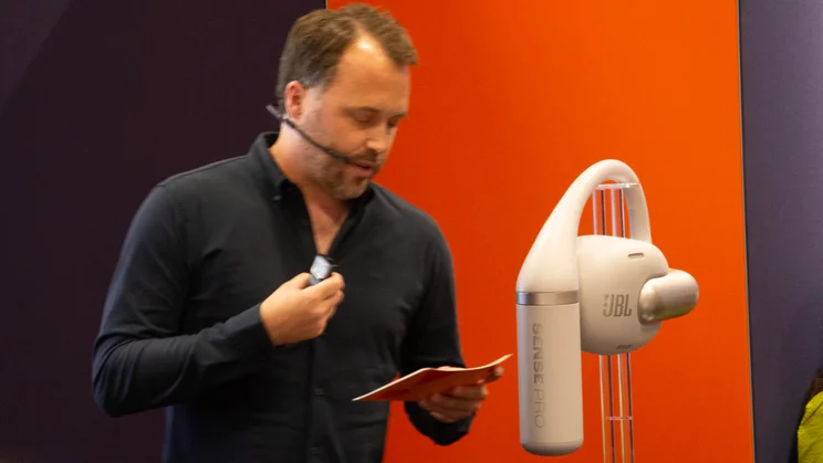 Harman Global Headphones Director Mikael Herje alongside a large-scale replica of the JBL Sense Pro open-ear headphones