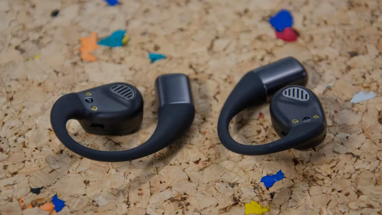 The JLab Epic Open Sport open-ear headphones upside down on a cork table to display the speaker drivers on the earpieces