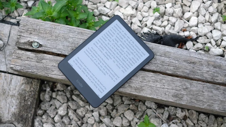 The Amazon Kindle Colorsoft displaying a page of text, on a wooden sleeper