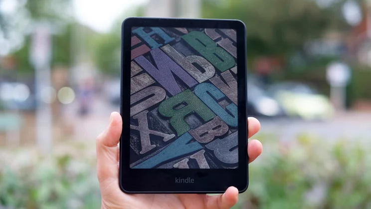 The Amazon Kindle Colorsoft being held in hand, showing a colourful lock screen
