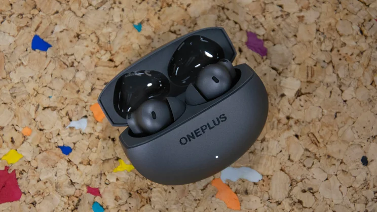 The OnePlus Buds 4 inside their charging case on a cork table