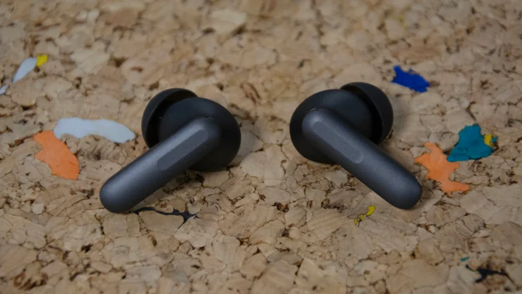 The OnePlus Buds 4 on a cork table with the stems of the earbuds pointing outwards