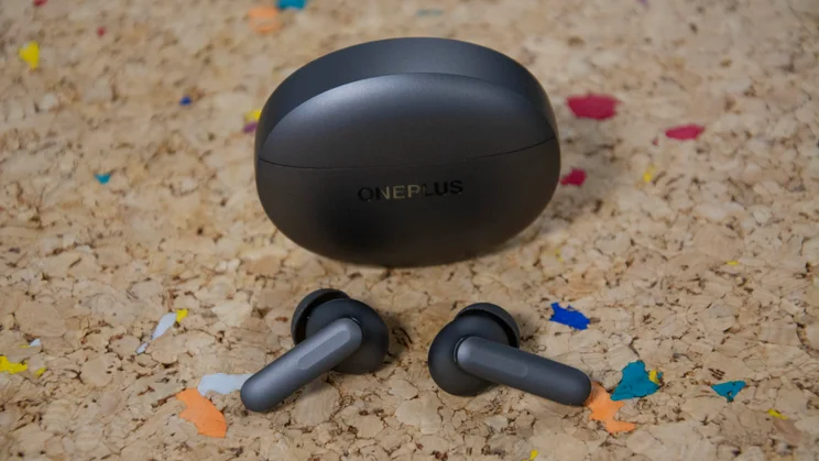 The OnePlus Buds 4 and their charging case on a cork table