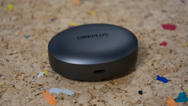 The OnePlus Buds 4's charging case lying flat on a cork table with the UBS-C port visible