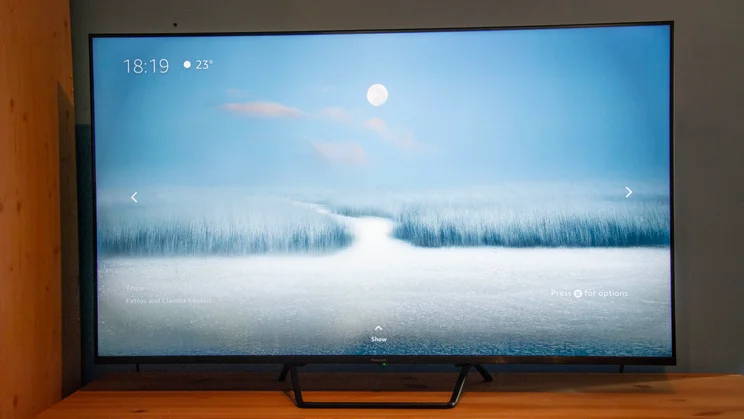 The Panasonic W95B Mini LED TV on a wooden cabinet displaying a snowy moonlit scene