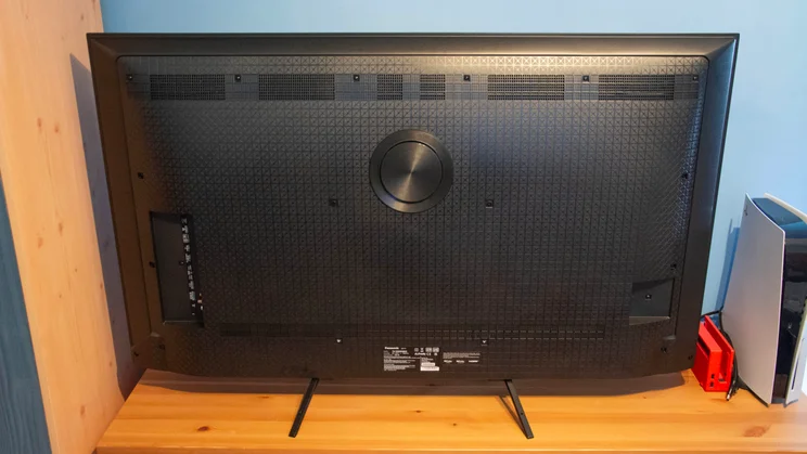 Rear view of the Panasonic W95B Mini LED TV on a wooden cabinet alongside a Nintendo Switch and PlayStation 5