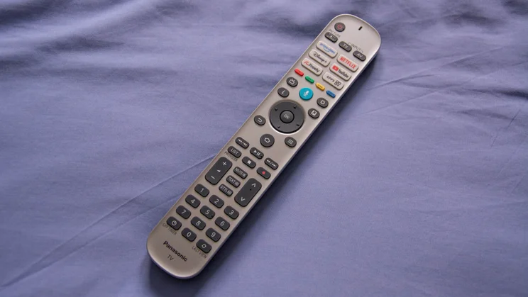 The remote control included with the Panasonic W95B Mini LED TV lying on a light blue pillow
