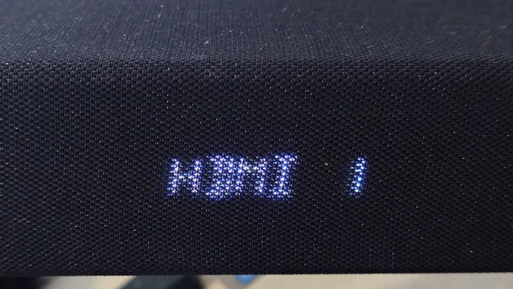 The digital display on the front of the Sharp HT-SBW55121 soundbar showing the source input to be HDMI 1