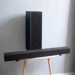 The Sharp HT-SBW55121 soundbar and subwoofer on a table with three wooden legs