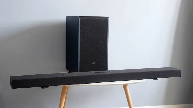 The Sharp HT-SBW55121 soundbar and subwoofer on a table with three wooden legs