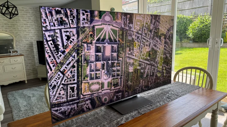 The TCL C8K QD-Mini LED TV shot from the left hand side while displaying a colourful wallpaper on screen