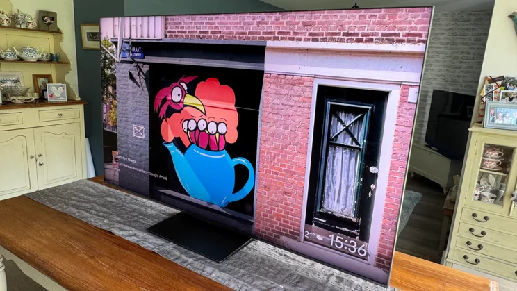 The TCL C8K QD-Mini LED TV displaying street art on a wall rom the right-hand side of a kitchen table