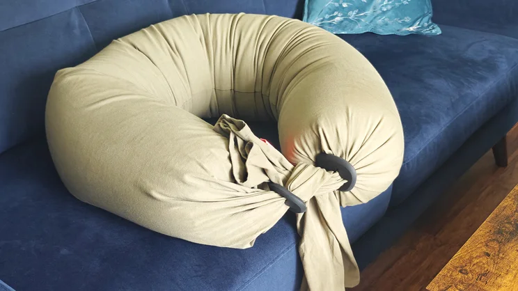 The Bbhugme pregnancy pillow curled up on a blue sofa