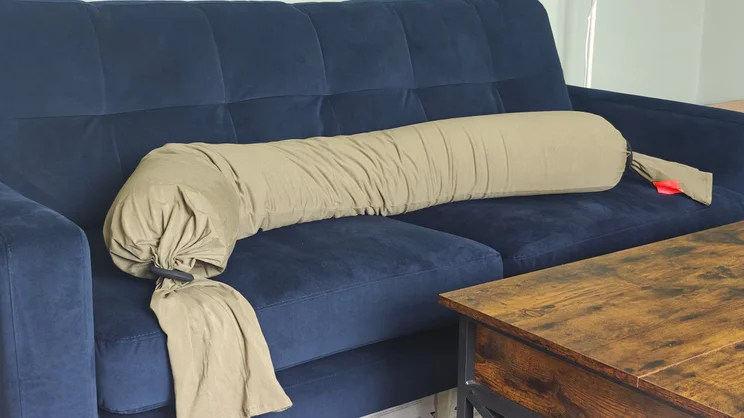 The Bbhugme pregnancy pillow laid out on a blue sofa