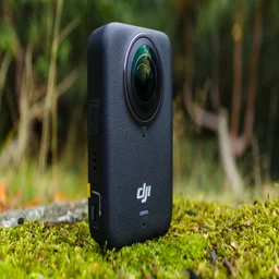The DJI Osmo 360, pictured on a mossy surface, from a left hand angle