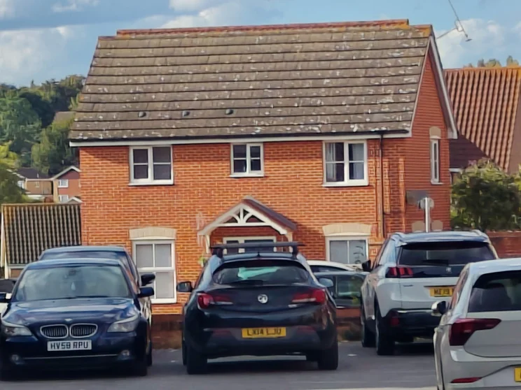 10x zoom of a red house with cars parked out front