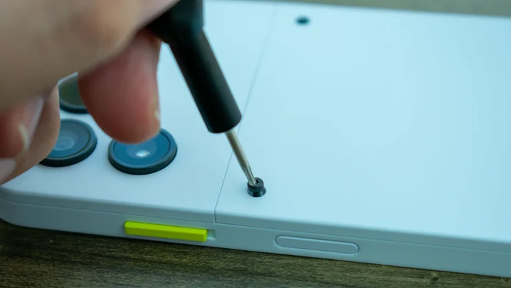 Hand using a screwdriver to remove the back of the Fairphone 6