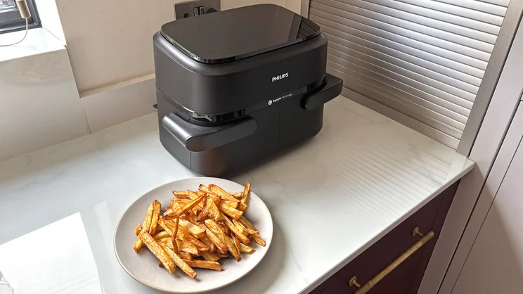 The Philips 1000 Series air fryer on a kitchen worktop, next to a plate of cooked chips