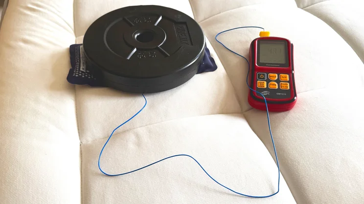 On the surface of the REM-Fit Natural Lux Hybrid mattress, a book and a weight hold down a thermocouple probe connected to a thermometer
