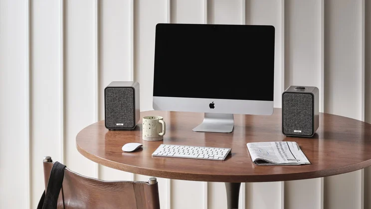 The Ruark MR1 Mk3 speakers, pictured on a circular table flanking an iMac computer