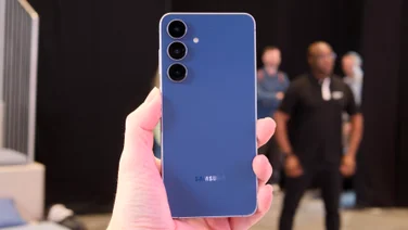 The blue Samsung Galaxy S25 FE held in hand picture from the rear