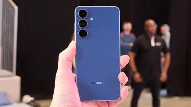 The blue Samsung Galaxy S25 FE held in hand picture from the rear