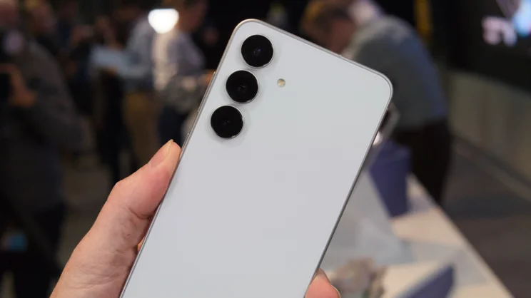 The rear of the white Samsung Galaxy S25 FE, held at an angle