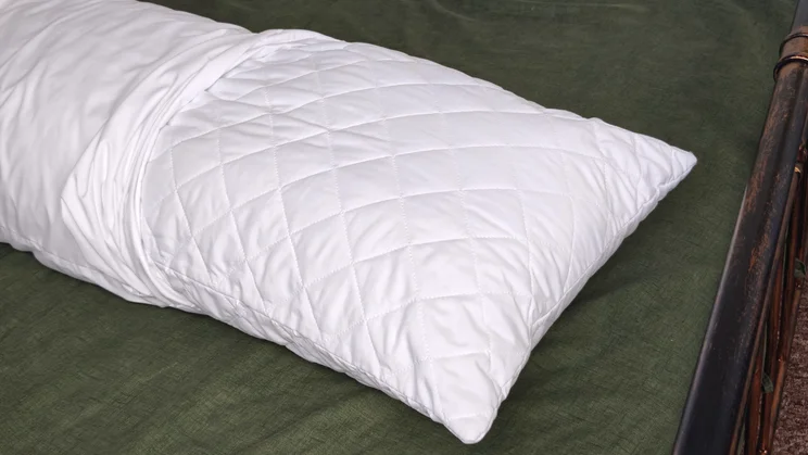 The Silentnight Body Support Pillow on a bed, with pillow case rolled back