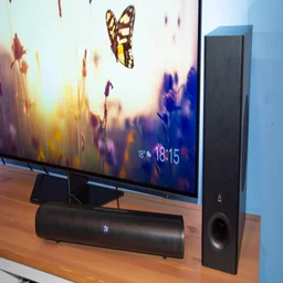 The Creative Stage Pro soundbar and subwoofer on a TV cabinet in front of the Philips OLED809