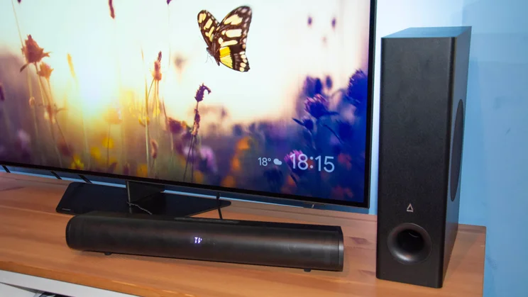 The Creative Stage Pro soundbar and subwoofer on a TV cabinet in front of the Philips OLED809