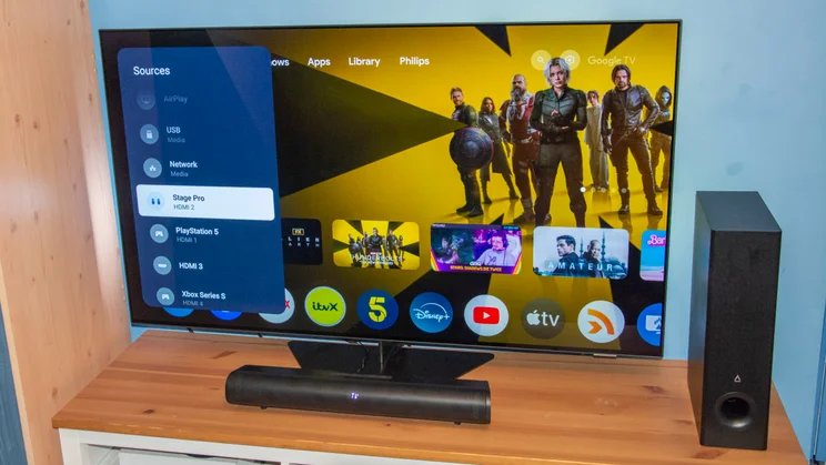 The Creative Stage Pro soundbar and subwoofer in front of the Philips OLED809 TV displaying the selection of HDMI sources