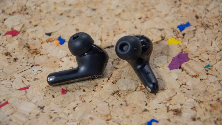 The JLab JBuds Pods ANC wireless earbuds side-by-side on a cork table