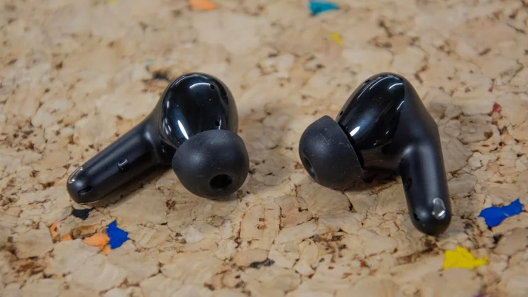 The JLab JBuds Pods ANC wireless earbuds on a cork table with their eartips pointing inwards