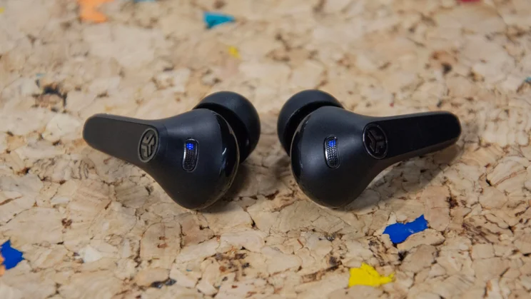 The JLab JBuds Pods ANC wireless earbuds on a cork table with their microphones clearly visible