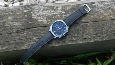 The Samsung Galaxy Watch 8 Classic lying on a wooden log in clock mode