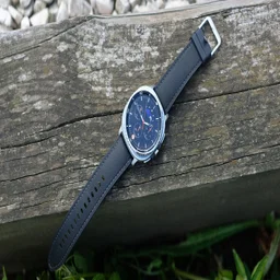 The Samsung Galaxy Watch 8 Classic lying on a wooden log in clock mode