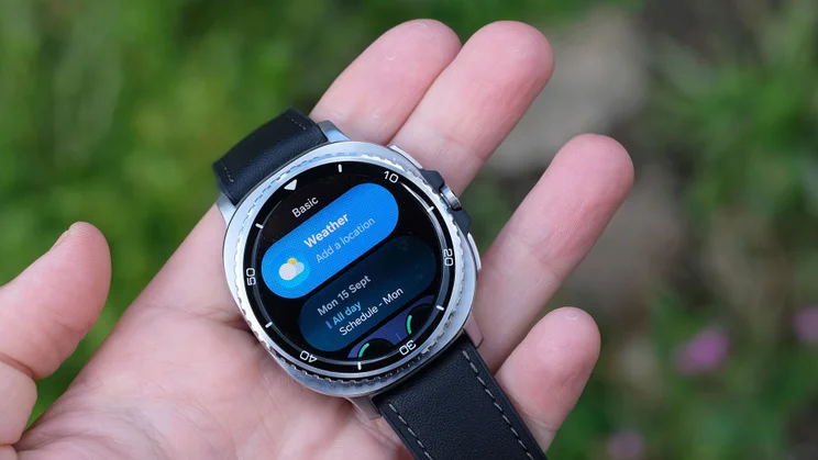 The Samsung Galaxy Watch 8 Classic being held in a person's hand showing the Weather app