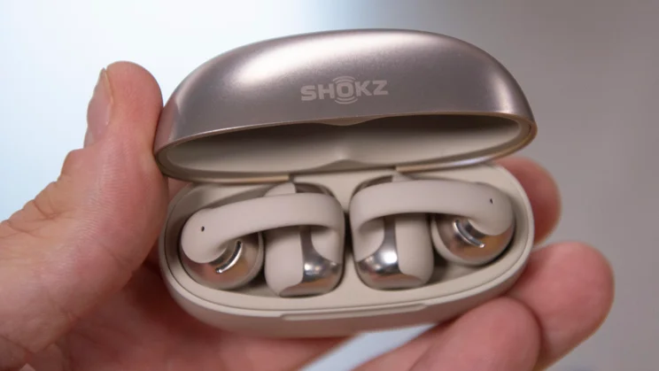 Shokz OpenDots One charging case, open, being held in fingertips